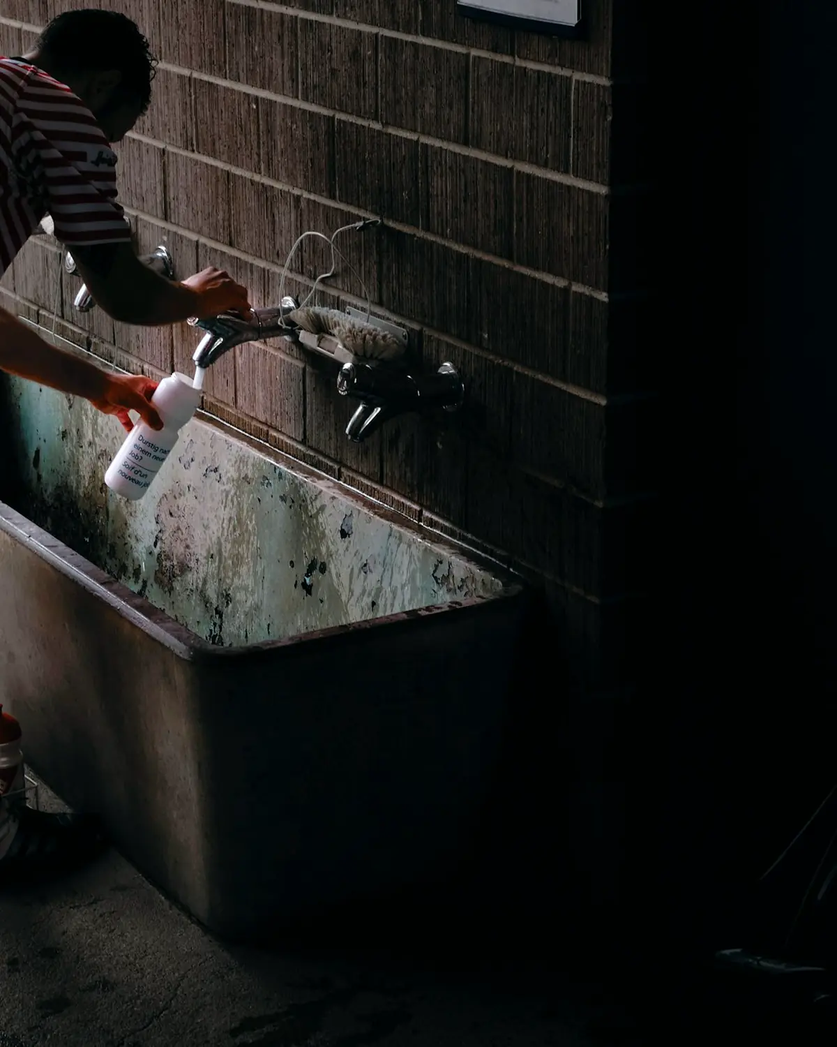 Plumber tightening a supply connection beneath a sink with a wrench